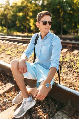 Gün batımı, yenilikçi şık giysiler içinde poz, tren rayları üzerinde oturan poz güzel şık gözlüklü,,