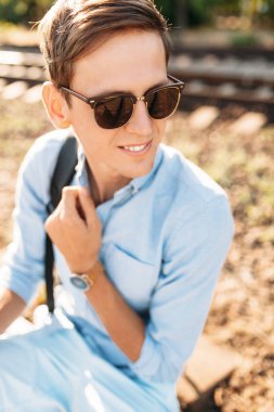 Gün batımı, yenilikçi şık giysiler içinde poz, tren rayları üzerinde oturan poz güzel şık gözlüklü,,