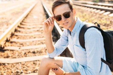 Gün batımı, yenilikçi şık giysiler içinde poz, tren rayları üzerinde oturan poz güzel şık gözlüklü,,