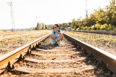 Gün batımı, yenilikçi şık giysiler içinde poz, tren rayları üzerinde oturan poz güzel şık gözlüklü,,