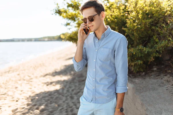 美丽时尚的商业家伙与眼镜 在海滩上摆姿势 时髦的电话交谈 工作度假 — 图库照片
