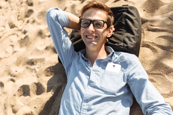 Poz, Genç adam gözlüklü, tatilde çalışmak kum, sahilde yatan,