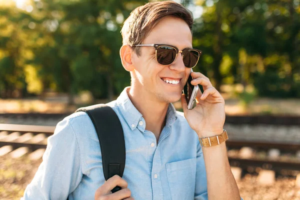 Tren rayları üzerinde günbatımında poz ve telefon, şık giysiler içinde poz hipster konuşmak güzel şık gözlüklü,,