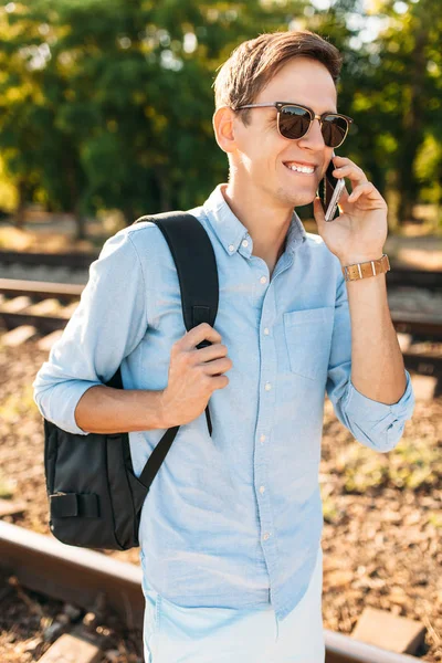 Tren rayları üzerinde günbatımında poz ve telefon, şık giysiler içinde poz hipster konuşmak güzel şık gözlüklü,,