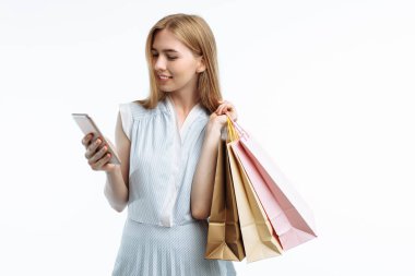 Telefon elinde poz, gözü üstünde ve, beyaz bir arka plan üzerinde satın almak seçerek şık ile genç kız, Hediyelik Çanta,,
