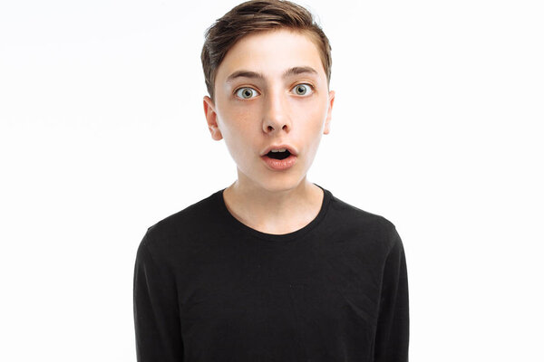 Photo emotional teenager, guy in black t-shirt, shows the emotion of surprise, on a white background,