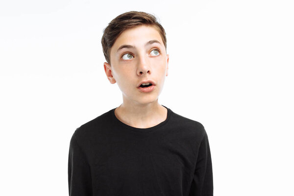 Photo emotional teenager, guy in black t-shirt, shows the emotion of surprise, on a white background,