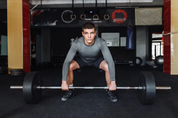 A man raises in the gym bar, the athlete trains
