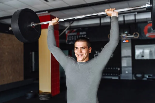 A man raises in the gym bar, the athlete trains