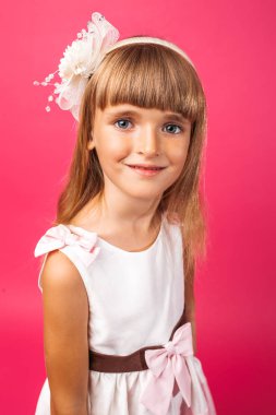 Stüdyoda pembe bir arka plan üzerinde güzel bir küçük kız portresi