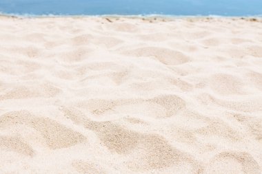 Kum yakın çekim, bulanık bir mavi deniz ya da okyanus, boş bir plaj arka planı