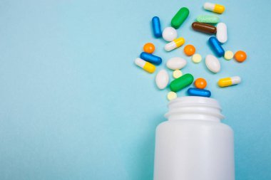 Çok renkli tablet ve kapsül, tablet, ilaç tıp hapları üzerinde mavi arka plan, analjezik hastalıklara karşı beyaz şişe