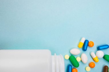 Çok renkli tablet ve kapsül, tablet, ilaç tıp hapları üzerinde mavi arka plan, analjezik hastalıklara karşı beyaz şişe