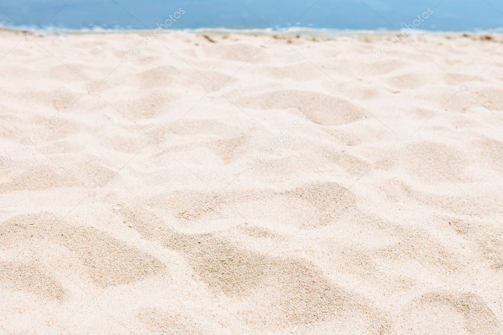 Sand close-up, against the background of a blurred blue sea or ocean, an empty beach