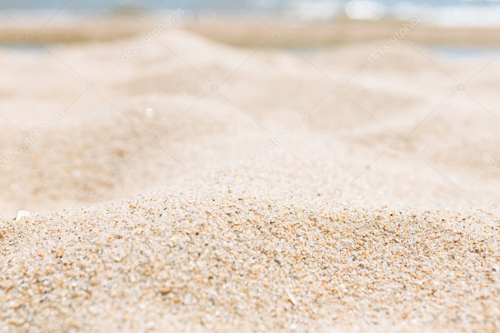 Sand close-up, against the background of a blurred blue sea or ocean, an empty beach