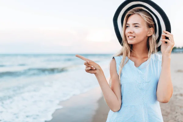 girl on the background of the sea, points to something with your finger