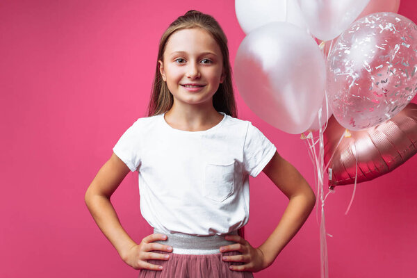 portrait of a girl with balloons in the Studio, on a pink background
