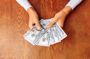 yakın çekim yüz dolar faturaları, bir sürü ahşap bir masa arka plan üzerinde tutan eller