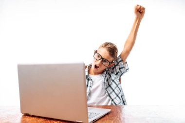 Bir dizüstü bilgisayar, mutlu zafer kadar stüdyoda oturup elini yükselterek bir masada oturan bir genç adam