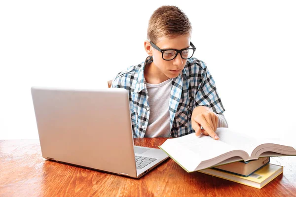 年轻男学生在工作室里用笔记本电脑和书坐在桌上做功课 — 图库照片