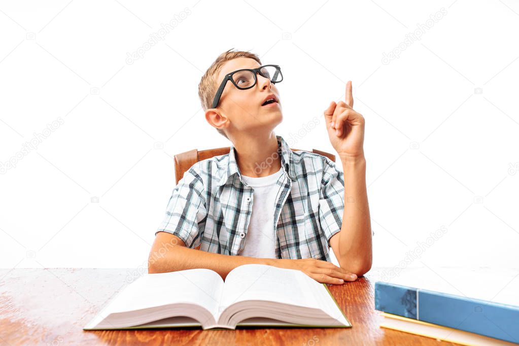 Portrait of a young man student or student who came up with the idea, sitting at a table with books in the Studio