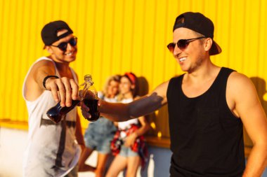 güzel çocuklar bir grup arkadaşıyla arka plan üzerinde portresi, cam şişe bir içkiyle ile gençlerin grup çekilin süpermarket, sarı bir arka plan üzerinde yakın arkadaş gel dolu, neşeli ruh hali, güneşli bir gün