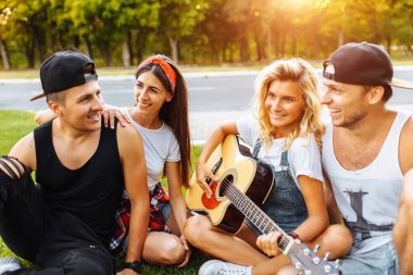 Gün batımı çimlere oturup, eğleniyor arkadaş iyi yaz ruh gitar Şirket