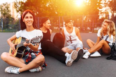 Bir grup arkadaşıyla birlikte bir skate Park asfalt üzerinde gün batımında eğleniyor, gitar, iyi yaz ruh