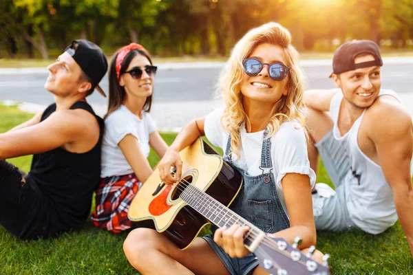 Compagnia Amici Che Divertono Tramonto Seduti Sull Erba Primo Piano — Foto Stock