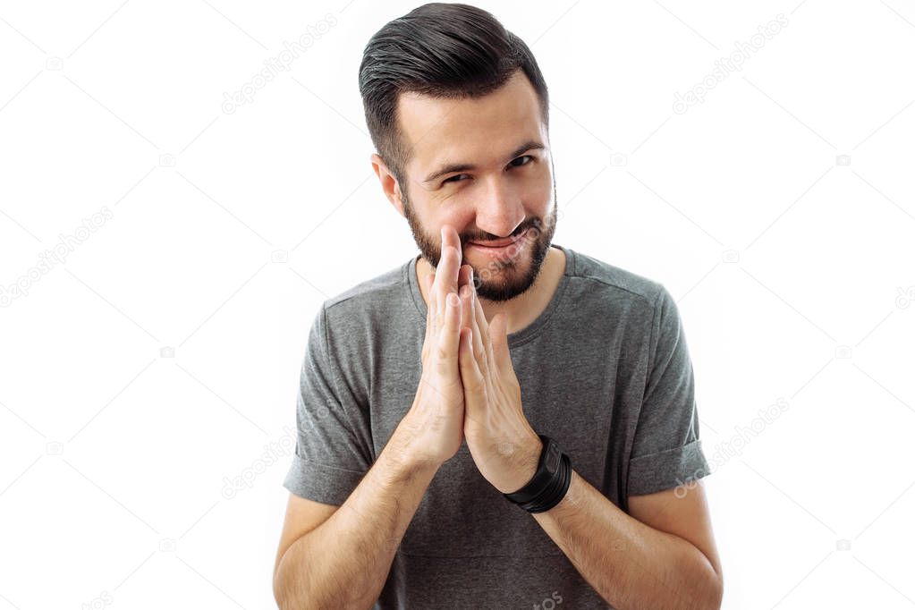 A business man with a beard, a gray t-shirt, with a crafty expression that he came up with, rubbing his hands in front of him, isolated on a white background