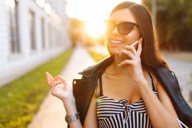 Genç bir kız bir başarılı, güzel bir gün batımı, arka plan üzerinde alışveriş, çanta el Evet sahiptir