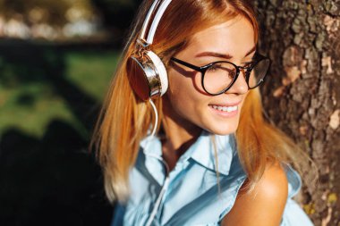 Gözlük takan kulaklıklarla, açık havada, müzik dinlemek güzel pozitif öğrenci kız portresi