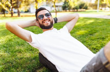 Beyaz gömlekli, iyi bir ruh hali içinde Park'ın bahçesinde dinlenmek şık hipster