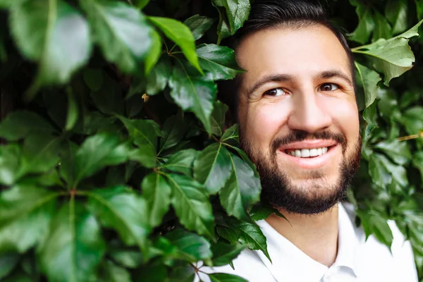 Snygg Hipster Med Skägg Vit Shirt Mot Lövfällande Vägg — Stockfoto