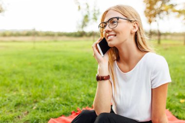 Evet ve üzerinde Park, kitap ve bir dizüstü bilgisayar ile kırmızı bir battaniyeye oturmuş genç bir güzel öğrenci gözlüklü, görüntü