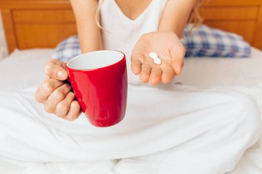 Hastalıktan uyanma bir tablet ve bir bardak su, onun yatağında oturan kız tutar