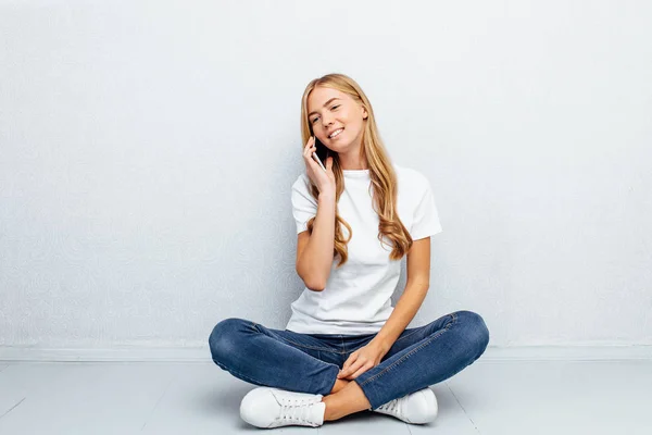 Hermosa Joven Con Una Camiseta Blanca Hablando Por Teléfono Sentado —  Fotos de Stock