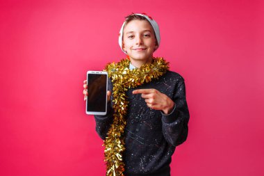 Tinsel bir boş cep telefonu ekran kırmızı bir arka plan üzerinde gösterilen ve boynunda ile Noel Baba şapkalı güzel teen