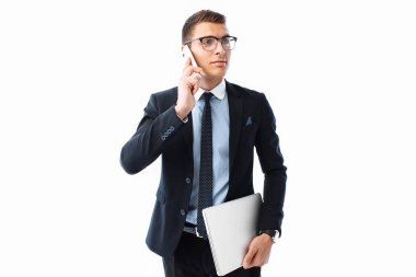 Business man, in a suit and glasses, talking on the phone and holding a laptop in his hand, on a white background clipart