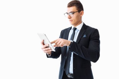 Bir takım elbise ve gözlük, kendine güvenen genç yakışıklı adam beyaz bir arka plan üzerinde duran bir dijital tablet üzerinde çalışan