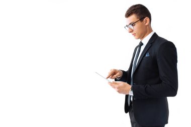 Bir takım elbise ve gözlük, kendine güvenen genç yakışıklı adam beyaz bir arka plan üzerinde duran bir dijital tablet üzerinde çalışan