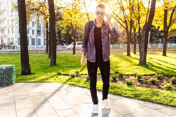 一个有公文包的年轻学生 穿着时髦的衣服 太阳镜 在公园散步 — 图库照片