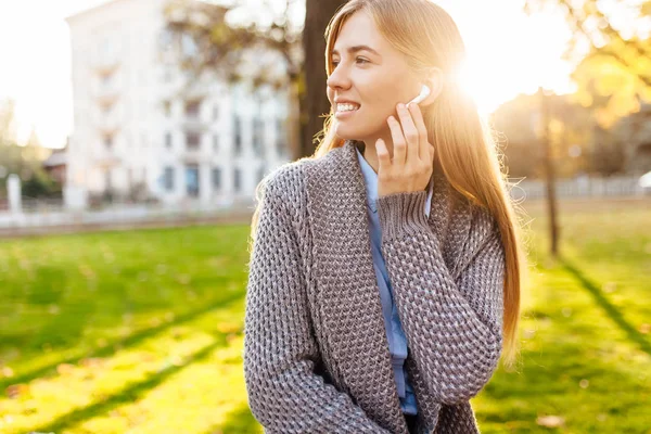 Young girl, in a good mood, listening to music with wireless headphones, on an autumn day, enjoying the good weather.