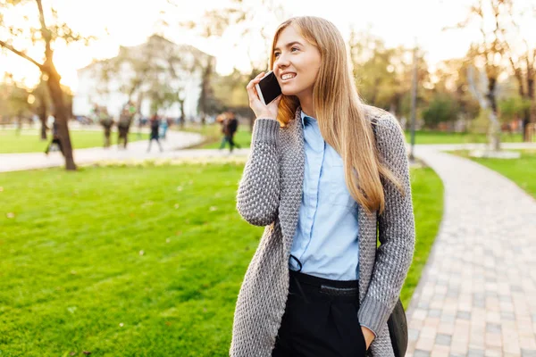 Portrait d'une femme heureuse, debout dans le parc, parlant au téléphone , — Photo