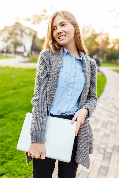 Gelukkig jongedame in het park met de laptop op zonsondergang achtergrond — Stockfoto