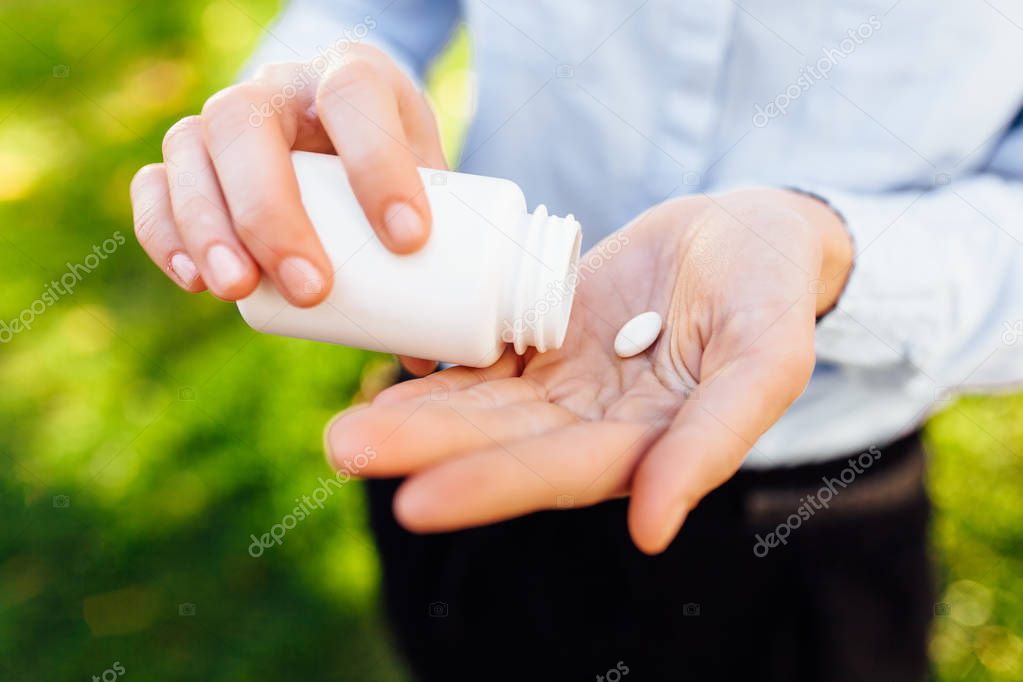 girl holding a jar of pills in her hands, outdoors