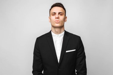 Yakışıklı genç iş adamı, klasik siyah elbiseli, gri bir arka plan üzerinde erkek portresi. İş kavramı, kariyer.