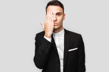 Yakışıklı genç iş adamı, klasik siyah elbiseli, Erkek portresi pozlar gri arka plan üzerinde gösterir. İş kavramı, kariyer.