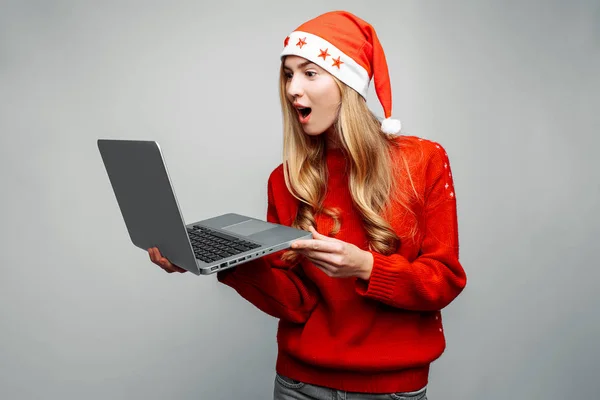 Sorprendido Chica Suéter Rojo Sombrero Santa Claus Utiliza Ordenador Portátil —  Fotos de Stock