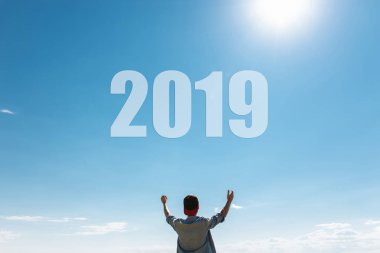 Dostum, mavi gökyüzü karşı adam ellerini gökyüzüne yeni 2019 yılı kavramı çeker. Noel